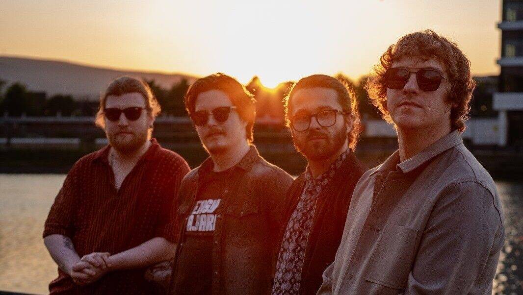 Vinery's band members performing outdoors at sunset, showcasing a vibrant music scene with a waterfront backdrop, perfect for promoting live music and event venues.