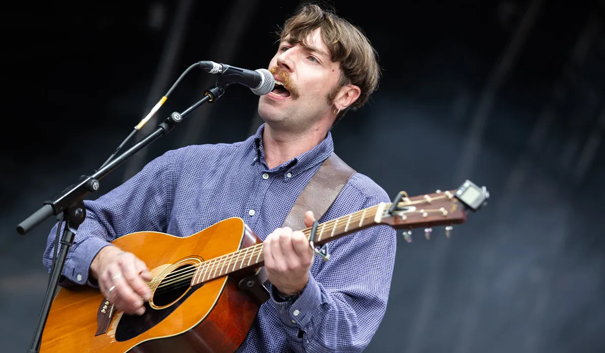 A male musician performing live with an acoustic guitar and singing into a microphone at Lavery's, showcasing vibrant music entertainment.